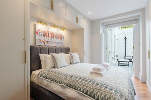 Ein modernes Schlafzimmer mit einem großen Bett, einem Wandbild und Blick ins Freie.