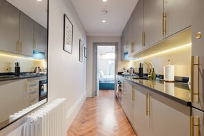 Eine moderne Küche mit einer zentralen Kochinsel, integrierten Geräten und Blick in das angrenzende Schlafzimmer.