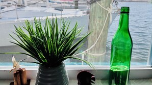 Ein Fenster mit Blick auf einen Hafen, eine grüne Flasche und ein Blumentopf.