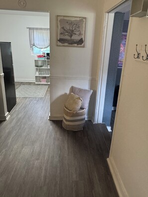 Ein Zimmer mit einem Sessel, einem Gemälde und einem Regal mit Gegenständen.