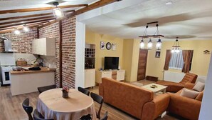 Un'ampia zona giorno con tavolo da pranzo, divano e angolo cottura sullo sfondo.