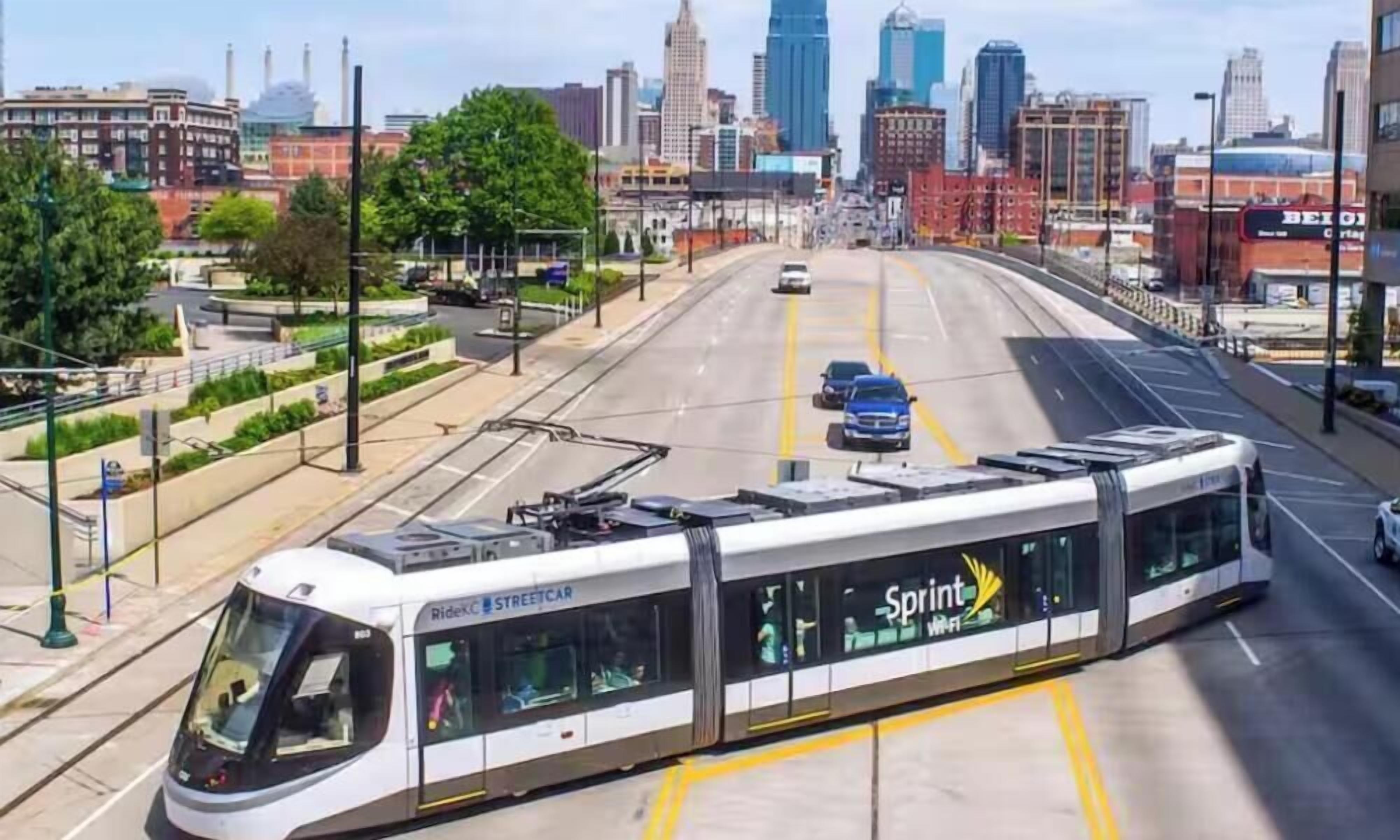 Un tramway moderne arborant le logo « Sprint », une route dégagée et une vue sur les gratte-ciel de la ville en arrière-plan.