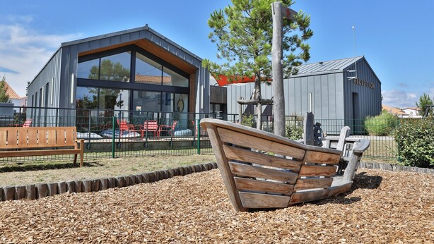 A modern building with large windows, a reception area, and a wooden bench in the foreground. - Luxury 8-person Private Pool Villa (Les Sables-d'Olonne)