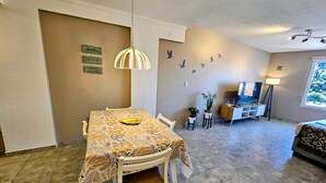 A dining area with a table, chairs, a hanging light fixture, a TV, and a window. - Refugio Urbano  Bariloche (San Carlos de Bariloche)