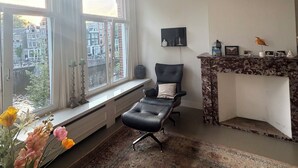 Une pièce dotée d’une grande fenêtre, d’un fauteuil en cuir noir, d’une cheminée et d’un tapis à motifs.