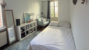 Une chambre à coucher avec un lit, une chaise, un bureau et une fenêtre.