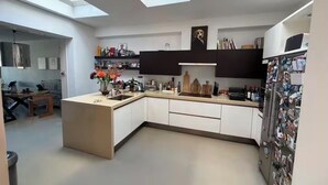 Une cuisine moderne dotée de fenêtres de toit, de meubles blancs et d’un îlot central.
