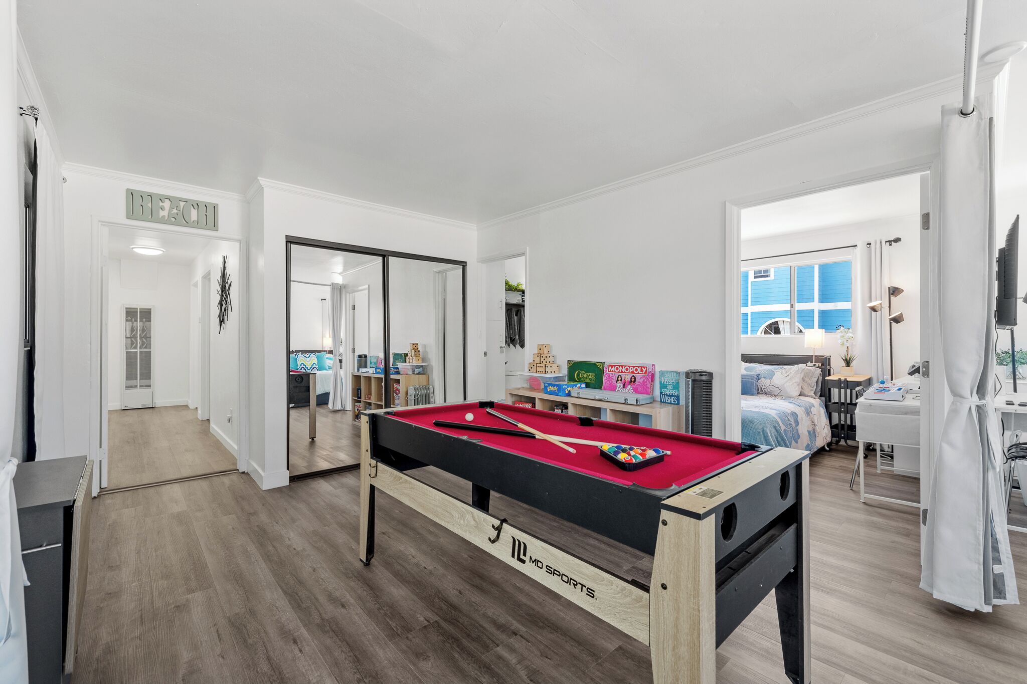 A pool table in a room with a bed, a desk, and a window.