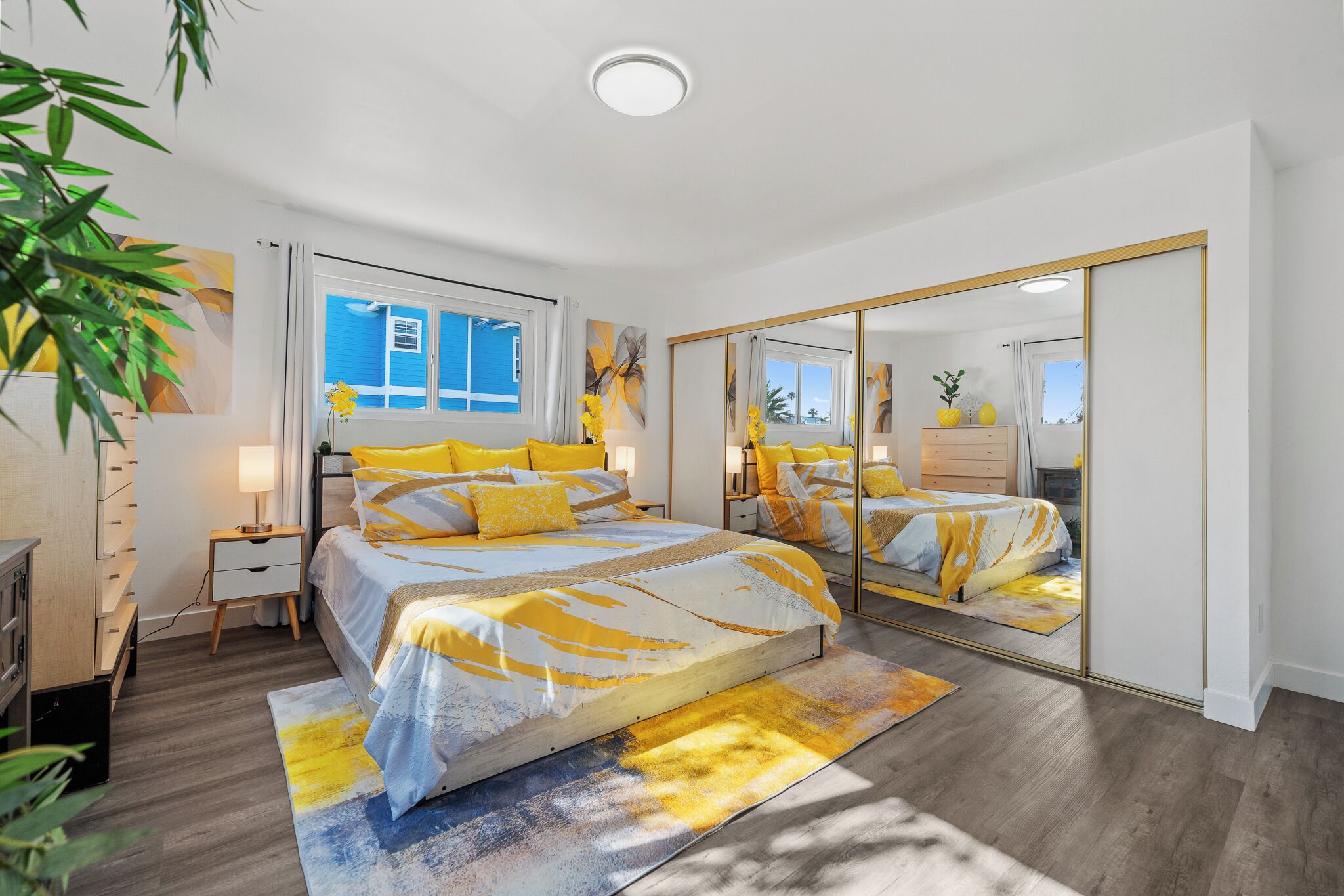 Un dormitorio con cama, mesitas de noche, un espejo y una ventana.