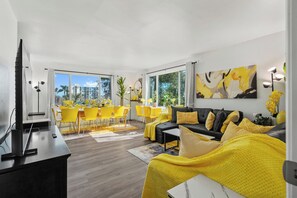 Ein modernes Wohnzimmer mit einer Couch, gelben Sesseln und einem Essbereich mit Tisch und Stühlen.