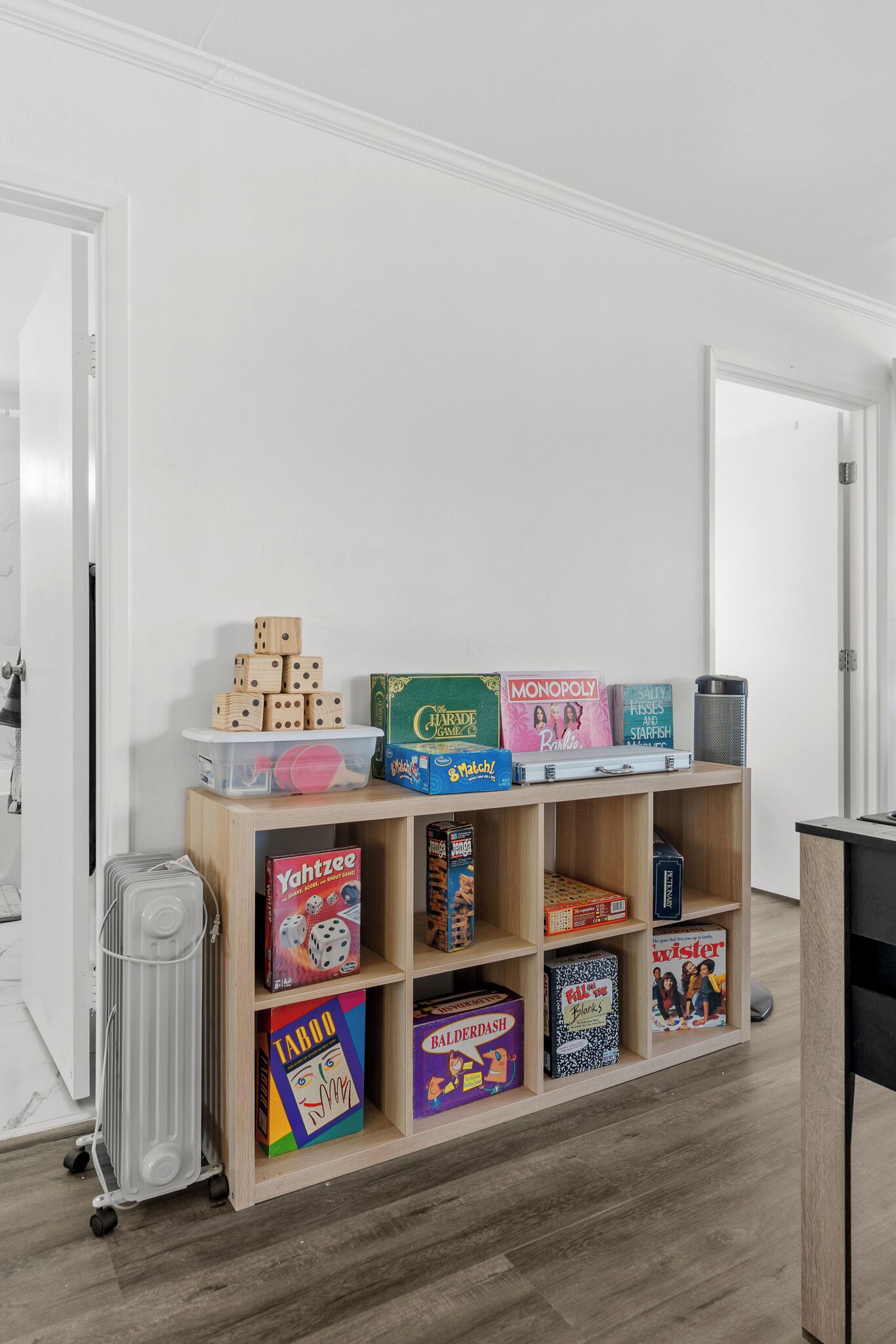 A room with a wooden shelf displaying various board games and a white door in the background.