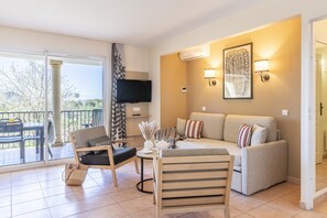A modern living room with a sofa, chairs, a small table with a vase, and a TV mounted on the wall. - Chic Countryside Stay With Balcony (Mallemort)