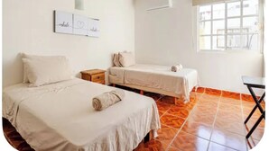 A room with two beds, a small table, a window, and a wall-mounted air conditioner. - Serene 2-bedroom house with AC in Puerto Vallarta great location. (Puerto Vallarta)