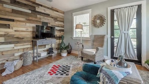 Un salon avec un mur en bois, un téléviseur, une cheminée, un canapé, une table basse et une fenêtre avec des rideaux.