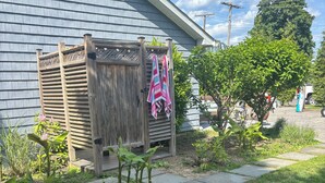 Een huis met een houten omheining, een waslijn met handdoeken en een tuin met diverse planten.