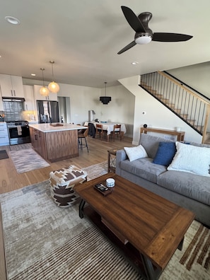 A modern kitchen with a central island, dining area, and a staircase leading to an upper level. - Cozy mountain townhome in beautiful Salida (Salida)