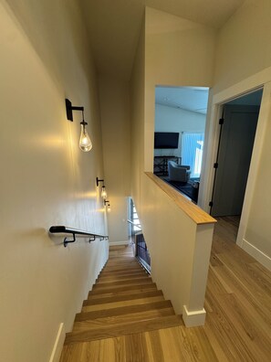A wooden staircase with light fixtures on the wall, leading to a room with a TV and a window. - Cozy mountain townhome in beautiful Salida (Salida)