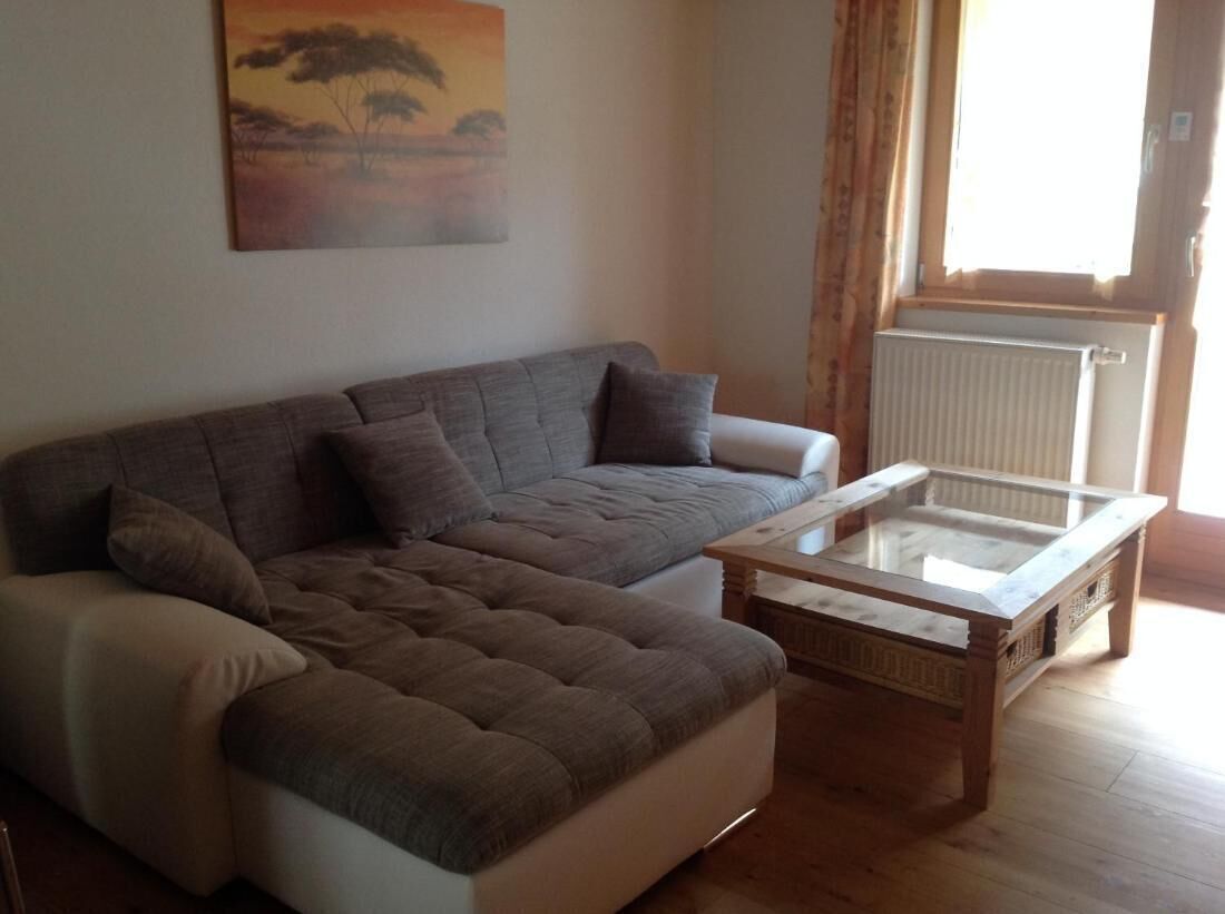A living room with a sofa, a glass-top coffee table, and a radiator.
