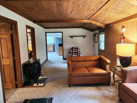 A cozy room with a brown leather sofa, a wooden ceiling, a lamp, and a fire extinguisher on the wall.. 2-bedroom cabin in serene Cleveland perfect for a relaxing getaway