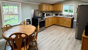 A modern kitchen with wooden cabinets, a dining table with chairs, a refrigerator, and a skylight. - 2-bedroom cabin in serene Cleveland perfect for a relaxing getaway (Cleveland)