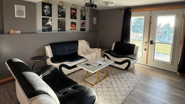 Ein modernes Wohnzimmer mit einer Sofagarnitur, einem Couchtisch und einem Deckenprojektor.