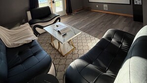 Ein modernes Wohnzimmer mit Projektor, einer großen Leinwand und einem Sofa.
