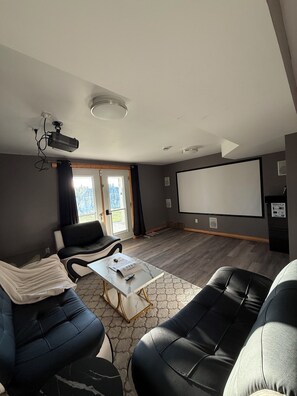 Una sala de estar moderna con proyector, una pantalla grande y un sofá.