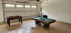 Ein Billardtisch mit grüner Spielvliesbahn und ein Tischfußballspiel mit Holzsockel und schwarzen Beinen.