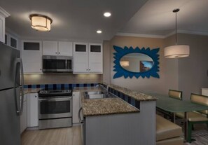 Una cucina moderna con elettrodomestici integrati, un'area pranzo con tavolo e sedie, e uno specchio a forma di sole blu davvero particolare al muro.