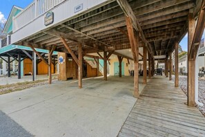 A covered outdoor area with a wooden deck, a concrete walkway, and a building with a sign. - Seas The Day, Waterpark, Close to Beach & Porch (Myrtle Beach)