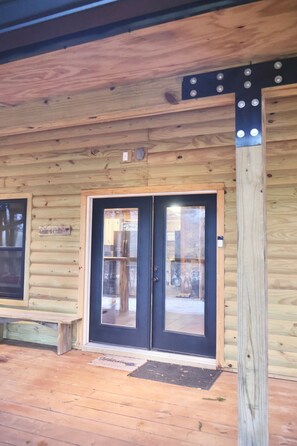 Une cabane en bois avec une porte à cadre noir, un banc à l’extérieur et une pancarte sur laquelle on peut lire : « Cabane de Glen ».