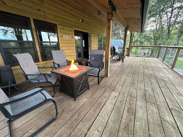 Une terrasse en bois avec des sièges d’extérieur et un foyer.