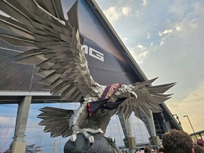 A large metallic sculpture resembling an eagle with outstretched wings, positioned in front of a modern building with a glass facade. - Braves local Smyrna Stay - Near Battery, Sleeps 6, RV parking option, EV charger (Smyrna)