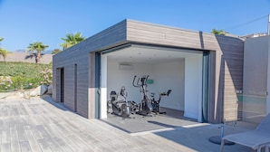 A modern outdoor gym with exercise equipment, a wooden deck, and a clear sky. - Lecci Villa With Outdoor Pools (Lecci)