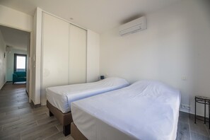 A bedroom with two beds, a wardrobe, an air conditioner, and a small table. - Lecci Villa With Outdoor Pools (Lecci)