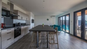 A modern kitchen with a dining area, large windows, and a view of the outdoors. - Lecci Villa With Outdoor Pools (Lecci)