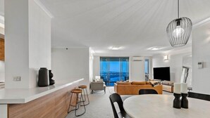 Een moderne woonkamer met een eethoek, een groot raam en een flatscreen televisie.