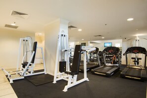 Une salle de sport équipée de divers appareils d’exercice, notamment des tapis de course, des appareils de musculation et un rameur.