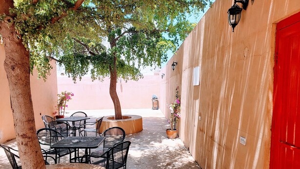 An outdoor seating area with tables and chairs, a tree, and a red door. - Excellent independent room 11, centrally located, independent and autonomous (Hermosillo)