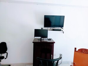 A room with a desk, a chair, a television, and a bed.
