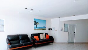 A living room with two black sofas, a painting of a beach, a door, and a ceiling light fixture. - Excellent independent room 11, centrally located, independent and autonomous (Hermosillo)