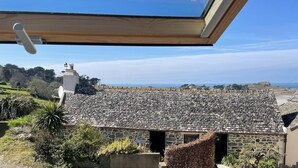 A stone building with a tiled roof, a skylight, and a view of the landscape. - Rental for 2 With Private Outdoor Space (Plougasnou)