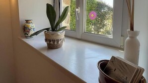 A window sill with a potted plant, a decorative vase, and a small bowl. - Rental for 2 With Private Outdoor Space (Plougasnou)