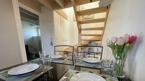 A dining area with a glass table, metal chairs, and a vase with flowers. - Rental for 2 With Private Outdoor Space (Plougasnou)
