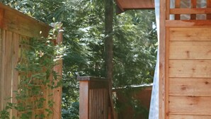 Eine Holzhütte mit geneigtem Dach, umgeben von Grün.