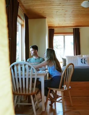 Un intérieur en bois comprenant une table et des chaises, un canapé et une fenêtre avec des rideaux.