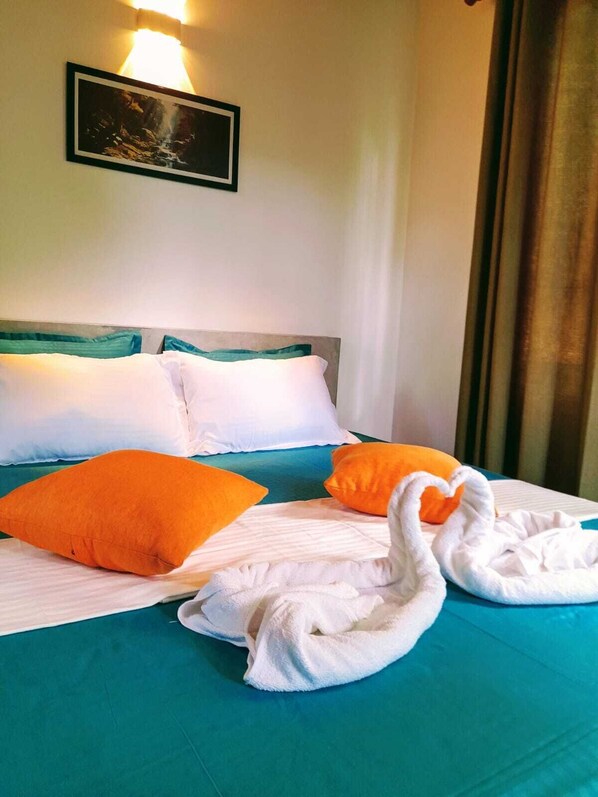 A hotel room with a bed, pillows, a framed picture on the wall, and a window with curtains.