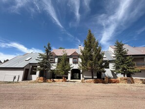 A two-story house with a metal roof, a front porch, and a driveway.