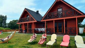 En rød bygning med balkon og græsplads med liggestole.