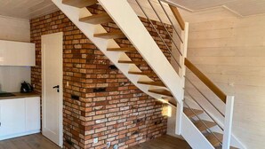 Et moderne interiør med en murstensvæg, en hvid dør og en trappe i træ.